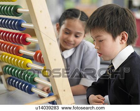 Stock Image - Elementary students using abacus in classroom. Fotosearch