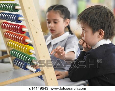 Stock Image - Elementary students using abacus in classroom. Fotosearch