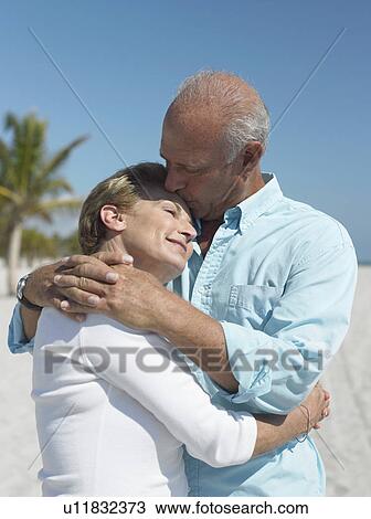 Embracing senior couple, kissing on tropical beach View Large Photo Image Stock Image - Embracing senior couple, kissing on tropical beach. Fotosearch
