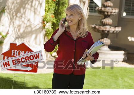 Estate agent using mobile phone at in front yard of house, portrait View Large Photo Image Stock Photo - Estate agent using mobile phone at in front yard of house, portrait. Fotosearch