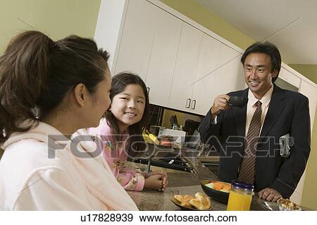 Stock Photo - Family at breakfast table, father ready for work. Fotosearch