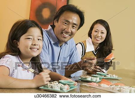 Stock Image - Family Eating Sushi Together, portrait. Fotosearch