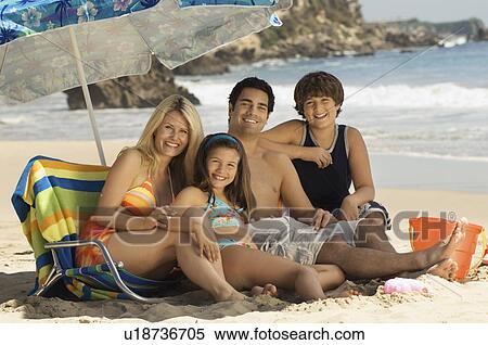 Family in swimwear on beach, sitting on lounge chair under parasol, portrait View Large Photo Image Stock Photography - Family in swimwear on beach, sitting on lounge chair under parasol, portrait. Fotosearch