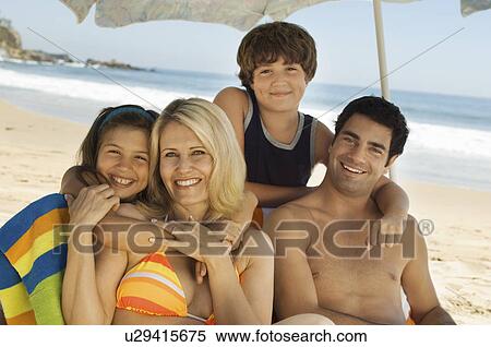 Stock Photography - Family in swimwear sitting together on beach, portrait. Fotosearch