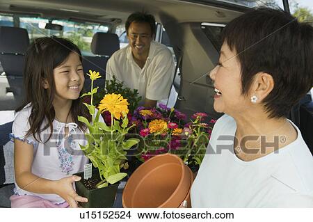 Picture - family loading flowers into back of SUV, close up. Fotosearch