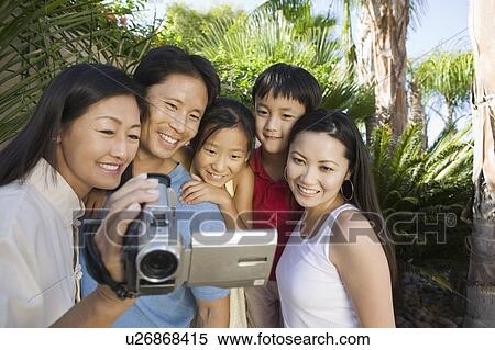 Stock Photography - Family Looking at Video Camera Screen in back yard, front view. Fotosearch
