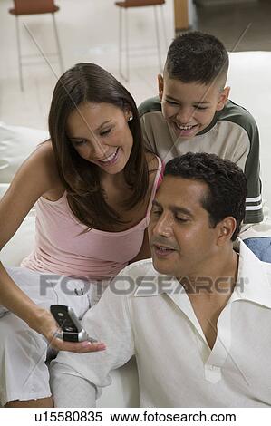 Family sitting on sofa looking at picture on cell phone View Large Photo Image Stock Photography - Family sitting on sofa looking at picture on cell phone. Fotosearch