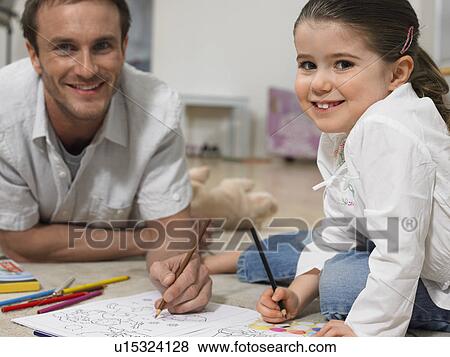 Stock Photo - Father and daughter (3-4) colouring in book on floor, (portrait). Fotosearch