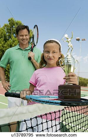 Father and Daughter by net on tennis court Holding Rackets and Trophy, portrait View Large Photo Image Stock Photography - Father and Daughter by net on tennis court Holding Rackets and Trophy, portrait. Fotosearch