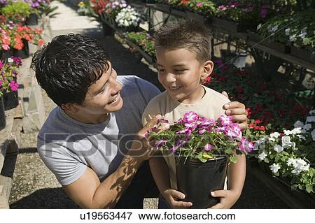 Stock Photo - Father and Son Shopping for Plants in plant nursery, close up. Fotosearch