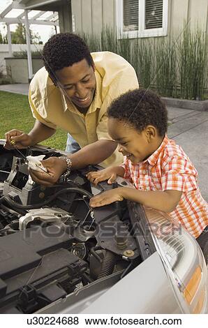 Father and young son inspecting car engine outside house View Large Photo Image Stock Photo - Father and young son inspecting car engine outside house. Fotosearch