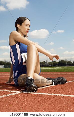 Stock Photo - Female athlete stretching on running track. Fotosearch