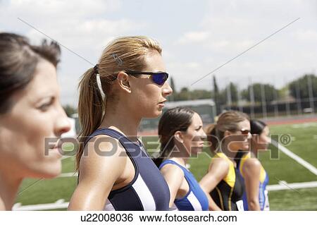 Stock Photograph - Female athletes lining up to start race, head and shoulders. Fotosearch