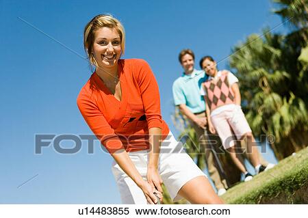 Stock Photography - Female golfer hitting ball from sand trap. Fotosearch