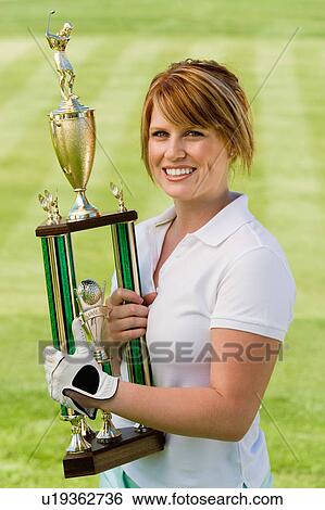 Stock Photograph - Female golfer holding trophy, (portrait). Fotosearch