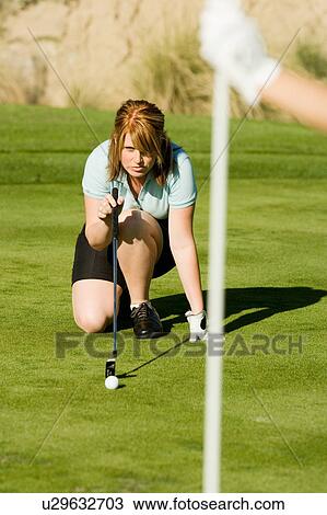 Female golfer putting while crouching on green View Large Photo Image Stock Image - Female golfer putting while crouching on green. Fotosearch