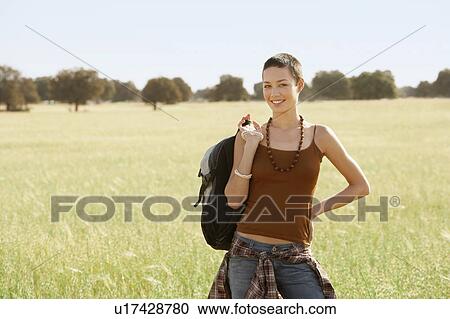 Female hiker holding backpack, standing in field, portrait View Large Photo Image Stock Image - Female hiker holding backpack, standing in field, portrait. Fotosearch