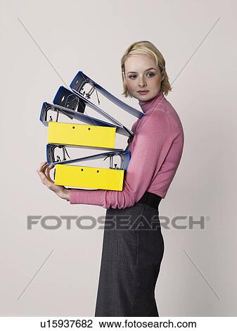Stock Image - Female office worker carrying empty binders, on white background. Fotosearch