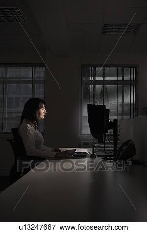 Female office worker using computer in darkened office, side view View Large Photo Image Stock Photo - Female office worker using computer in darkened office, side view. Fotosearch