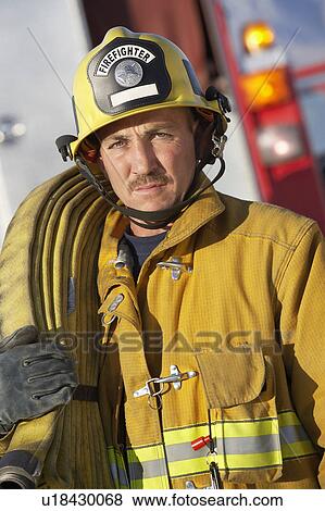Stock Photo - Fire fighter holding hose on shoulder. Fotosearch