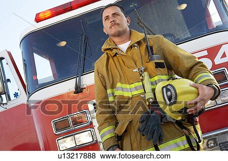 Stock Photo - Fire fighter standing in front of fire engine. Fotosearch