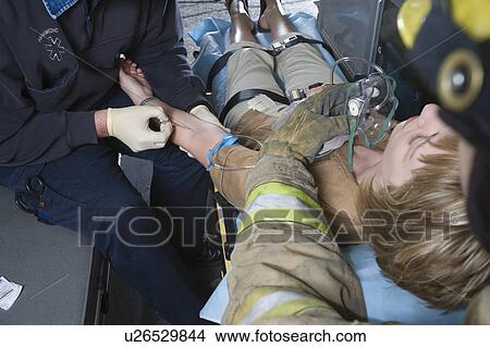 Picture - Firefighter and paramedic helping woman in ambulance. Fotosearch