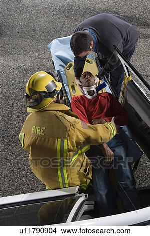 Firefighter and paramedic rescuing car accident victim View Large Photo Image Picture - Firefighter and paramedic rescuing car accident victim. Fotosearch