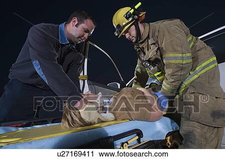 Stock Image - Firefighter and paramedic rescuing car accident victim. Fotosearch