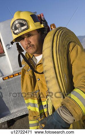 Stock Image - Firefighter carrying hose. Fotosearch