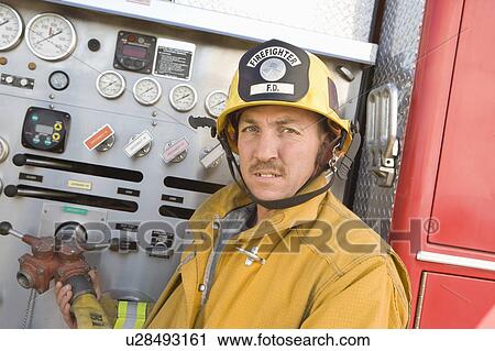 Stock Image - Firefighter operating engine. Fotosearch