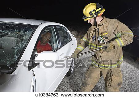 Stock Image - Firefighter rescuing car accident victim. Fotosearch