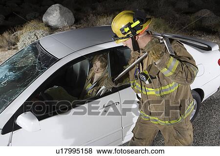 Stock Photo - Firefighter rescuing car accident victim. Fotosearch