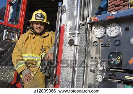 Stock Photograph - Firefighter sits on fire engine. Fotosearch