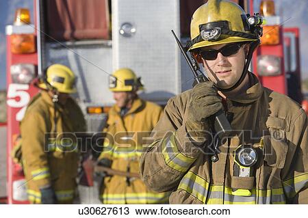 Stock Image - Firefighter using walkie talkie. Fotosearch