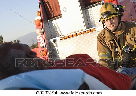 Firefighter with injured person on stretcher View Large Photo Image Picture - Firefighter with injured person on stretcher. Fotosearch