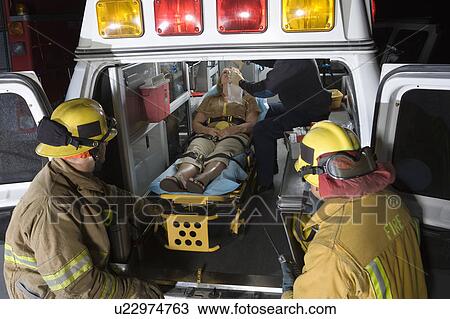Firefighters looking at victim in ambulance View Large Photo Image Stock Image - Firefighters looking at victim in ambulance. Fotosearch