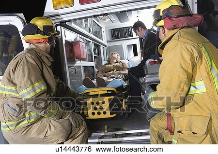 Firefighters looking at victim in ambulance View Large Photo Image Stock Photograph - Firefighters looking at victim in ambulance. Fotosearch