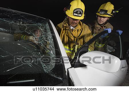 Picture - Firefighters rescuing car accident victim. Fotosearch