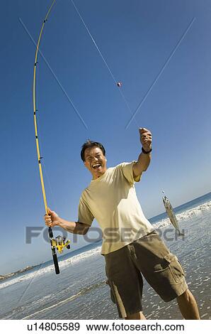 Stock Photo - Fisherman displaying catch at ocean, (portrait). Fotosearch
