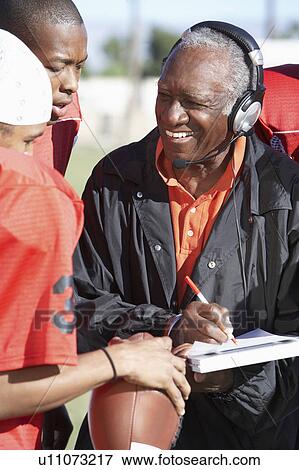 Stock Photo - Football Coach with clipboard Talking to Players. Fotosearch