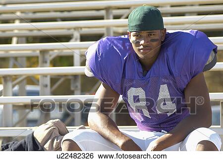 Stock Photograph - Football player sitting on bleachers. Fotosearch