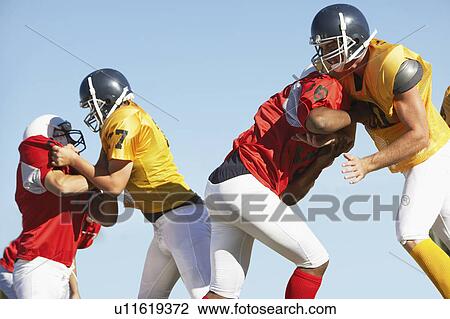 Stock Image - Football Players blocking during game. Fotosearch