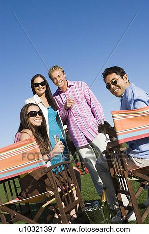 Stock Photo - Four friends toasting on polo field, portrait. Fotosearch