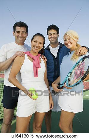 Stock Photography - Four mixed doubles tennis players by net at tennis court, portrait. Fotosearch