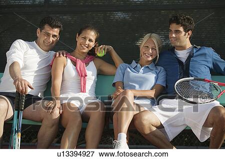 Four mixed doubles tennis players sitting on bench at tennis court, portrait View Large Photo Image Stock Photo - Four mixed doubles tennis players sitting on bench at tennis court, portrait. Fotosearch