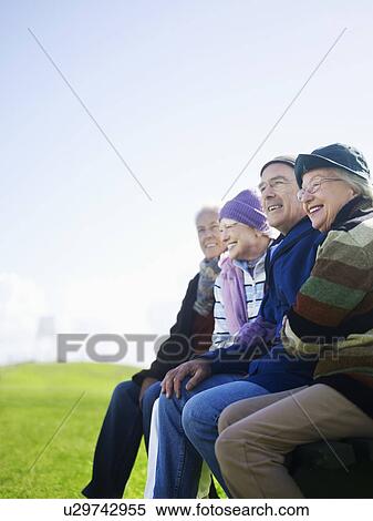 Four senior friends sitting outdoors, laughing View Large Photo Image Stock Photography - Four senior friends sitting outdoors, laughing. Fotosearch