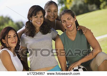 Stock Photo - Four women in park, one woman holding soccer ball.. Fotosearch