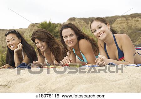 Four women lying down side by side on the Beach, portrait View Large Photo Image Stock Photograph - Four women lying down side by side on the Beach, portrait. Fotosearch