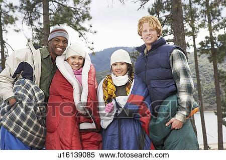 Four young adults wrapped in sleeping bags, standing by lake View Large Photo Image Stock Photography - Four young adults wrapped in sleeping bags, standing by lake. Fotosearch