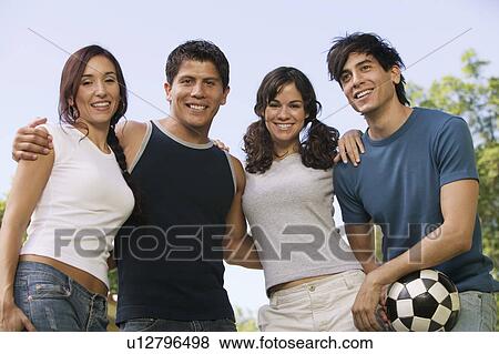 Stock Photo - Four young people at park, man holding soccer ball.. Fotosearch